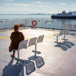 Une femme assise de dos sur un banc prête à partir en voyage